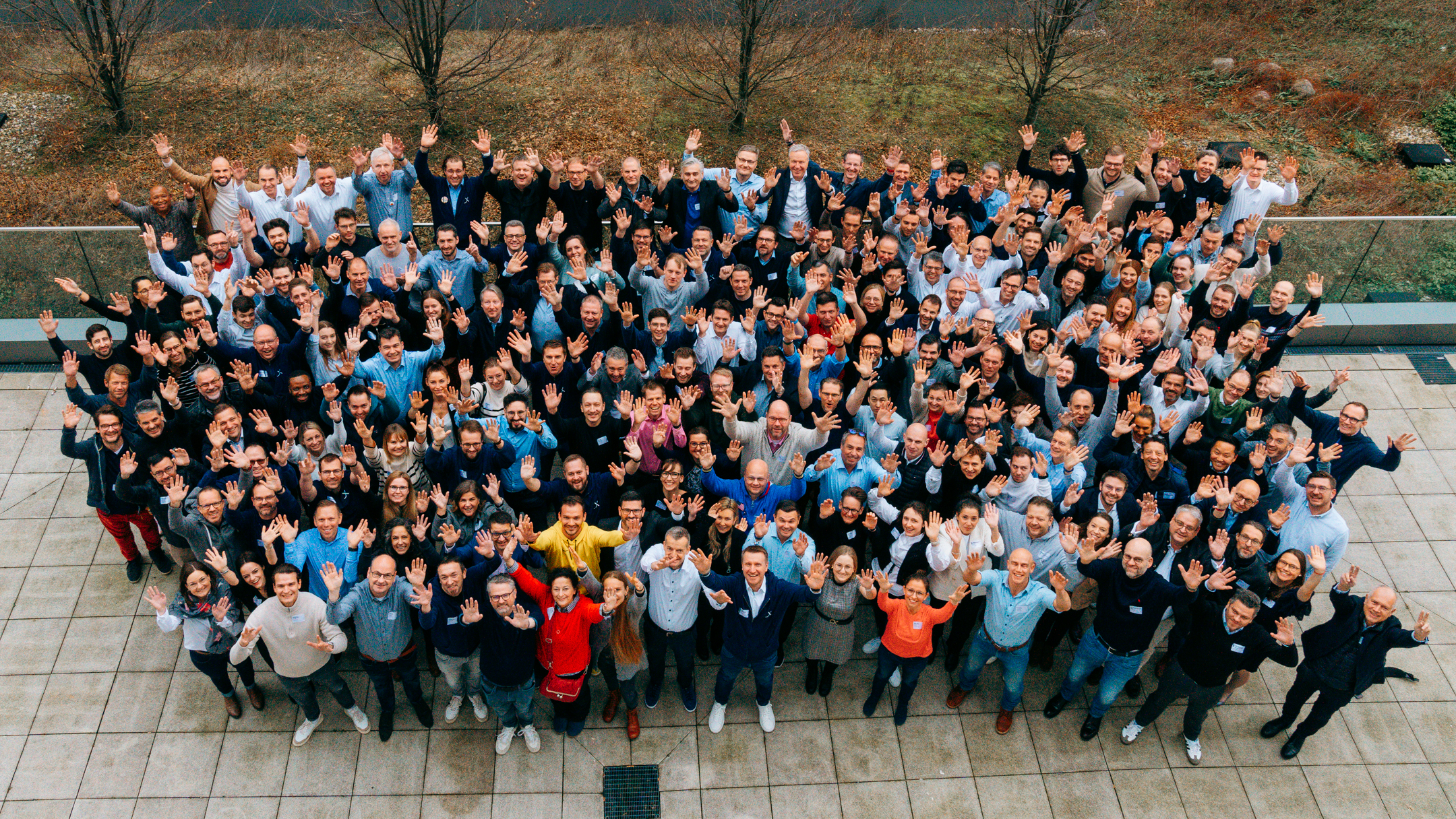 Group of diverse people waving outdoors for a photo