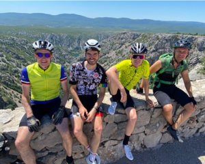Four cyclists resting on mountain summit.
