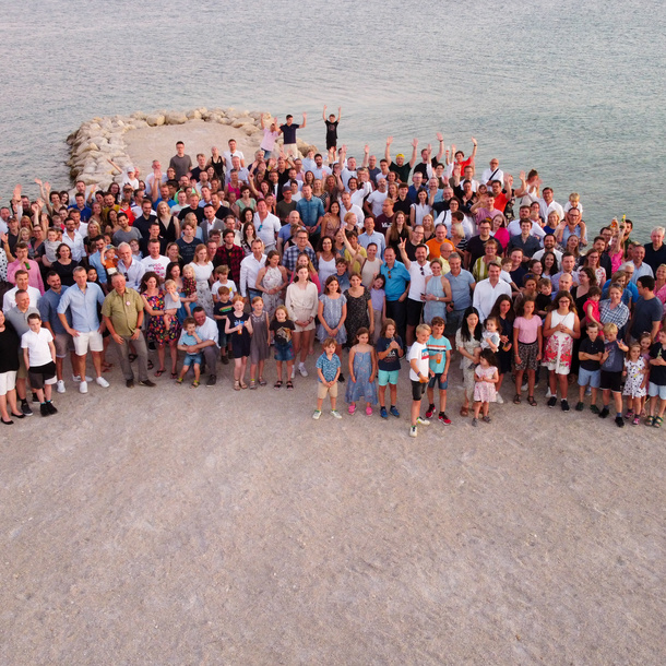 Large group of people gathered outdoors by water.