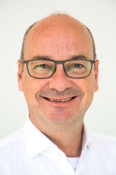 Man in glasses smiling against white background.